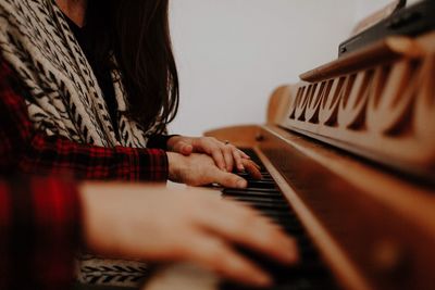 Close-up of friends playing piano at home