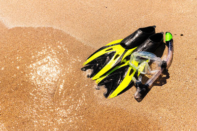Snorkeling equipment on the sand with ocean waves splashing the water. 