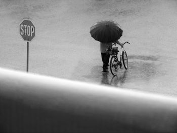 Man with bicycle standing on road during rainy season