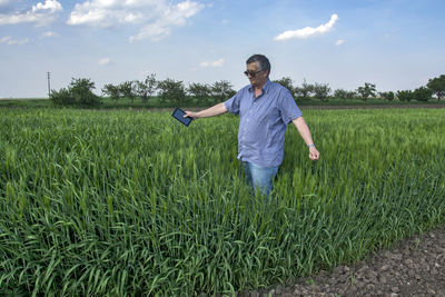 Senior man sanding in farm against sky