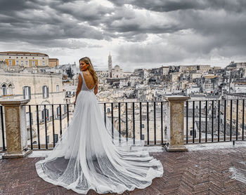 Woman standing on field against cityscape with sky in background