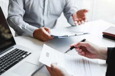 Midsection of man using mobile phone while sitting on table