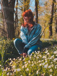 Young woman sitting amidst plants in forest