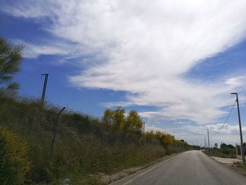 Road amidst field against sky