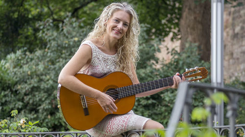 Portrait of a smiling young woman playing guitar