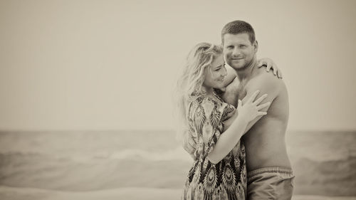 Couple kissing at beach against sky