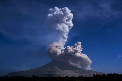 Low angle view of smoke emitting from mountain against sky