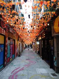 Illuminated lanterns hanging on footpath amidst buildings in city