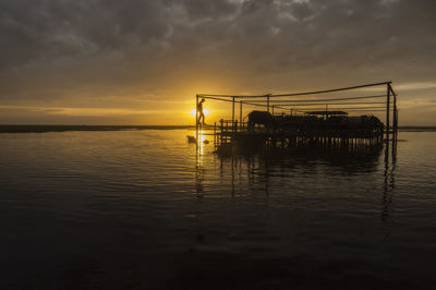 Silhouette pier over sea against sky during sunset