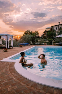 Rear view of couple in swimming pool against sky