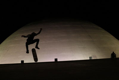 Silhouette of people on landscape against sky at night