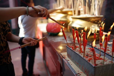 Cropped image of woman burning incense at altar
