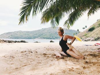 Full length of woman exercising on beach