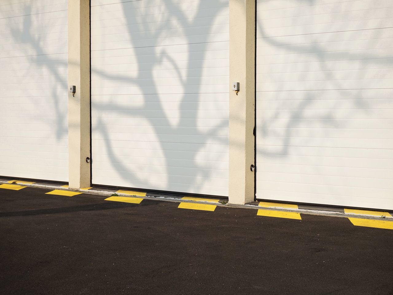 yellow, built structure, architecture, street, road marking, day, wall - building feature, road, transportation, door, wall, safety, building exterior, outdoors, no people, shadow, textured, protection, sunlight, window