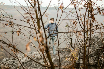 Teenager walking on rock formation seen from dry plants