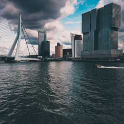 Bridge over river by buildings in city against sky