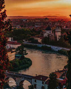 High angle view of townscape by river at sunset