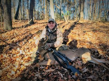 Portrait of smiling army soldier sitting in forest during winter