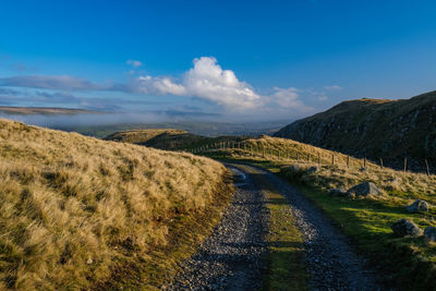 Road leading towards mountains against sky