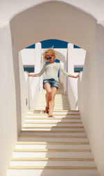 Low angle view of smiling young woman moving down building steps