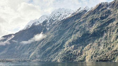 Scenic view of sea and snowcapped mountains against sky