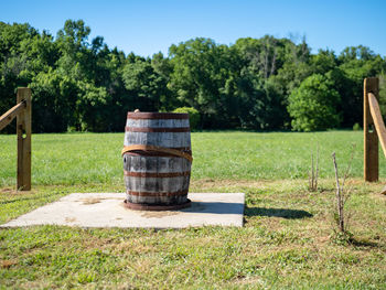 Wooden post on field by trees