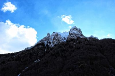 Low angle view of snowcapped mountain against blue sky