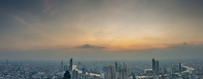 Aerial view of buildings against cloudy sky during sunset