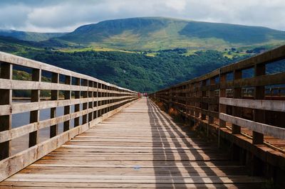 Narrow footbridge leading to lush landscape