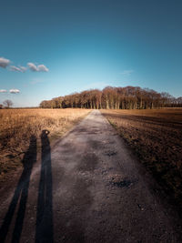 Road amidst field against sky