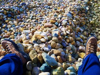 Low section of woman standing on pebbles at beach