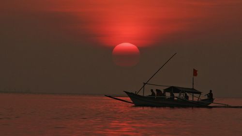 Silhouette boat in sea against sky during sunset