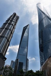 Low angle view of skyscrapers against cloudy sky