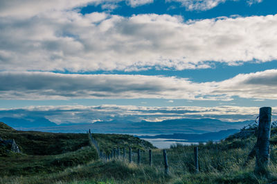 Scenic view of field by sea against sky