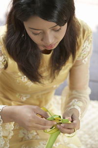 High angle view of woman weaving leaves while sitting in gazebo