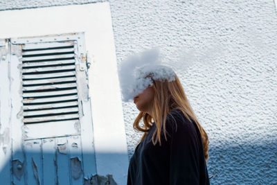 Woman standing against wall in winter