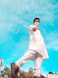 Low angle view of man holding coffee against sky