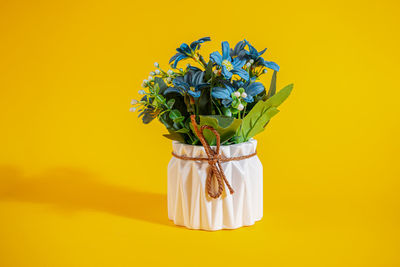 Close-up of flower vase against yellow background