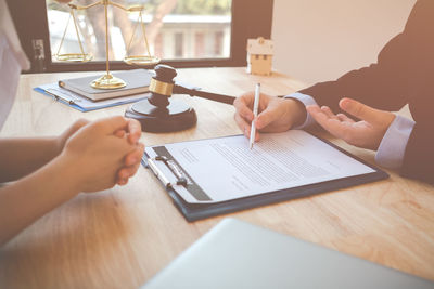 Midsection of lawyer having meeting with client in office