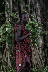 Portrait of woman standing by tree