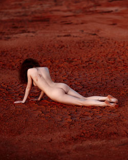 Side view of woman lying on sand