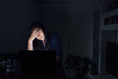 Tired young woman with laptop at home