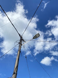 Low angle view of electricity pylon against blue sky