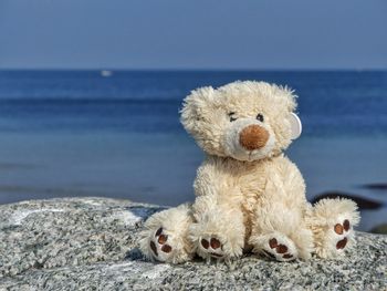Close-up of teddy bear against calm blue sea