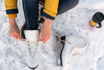 Young woman putting on ice skates. female hands tying laces. close up