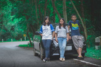 Full length portrait of friends sitting on tree