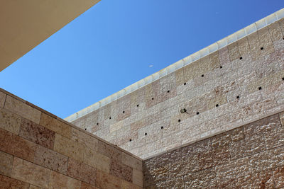 Angled perspective inside a patio, with stone texture and clear blue sky., and a lone seagull.