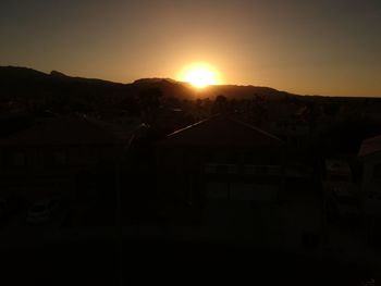 Silhouette buildings against sky during sunset