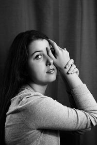 Portrait of young woman standing against curtain