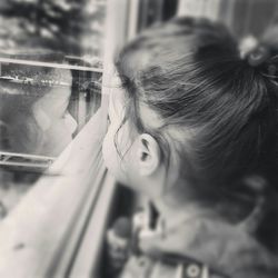 Close-up of girl looking through window